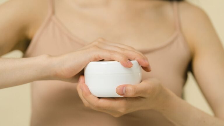 Person holding a white jar of moisturising cream